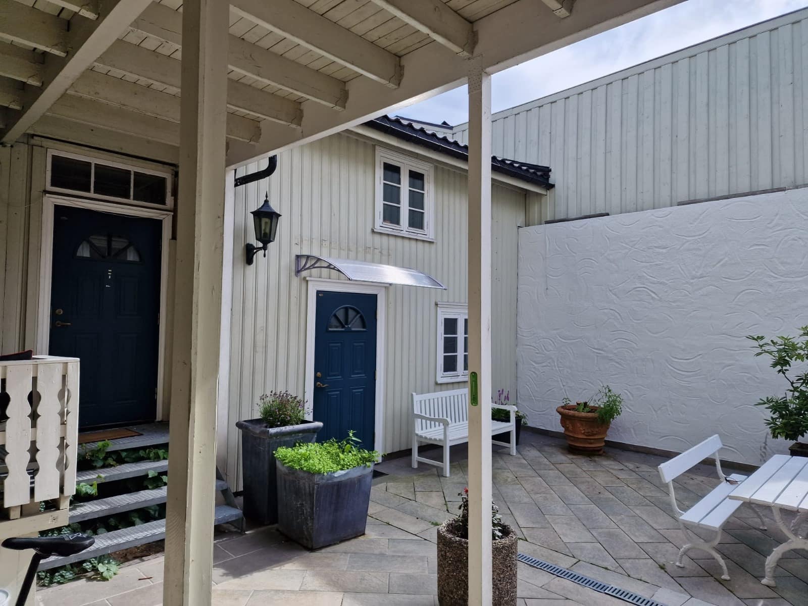 Bakgård med nymalt kremhvit kledning og blå dører