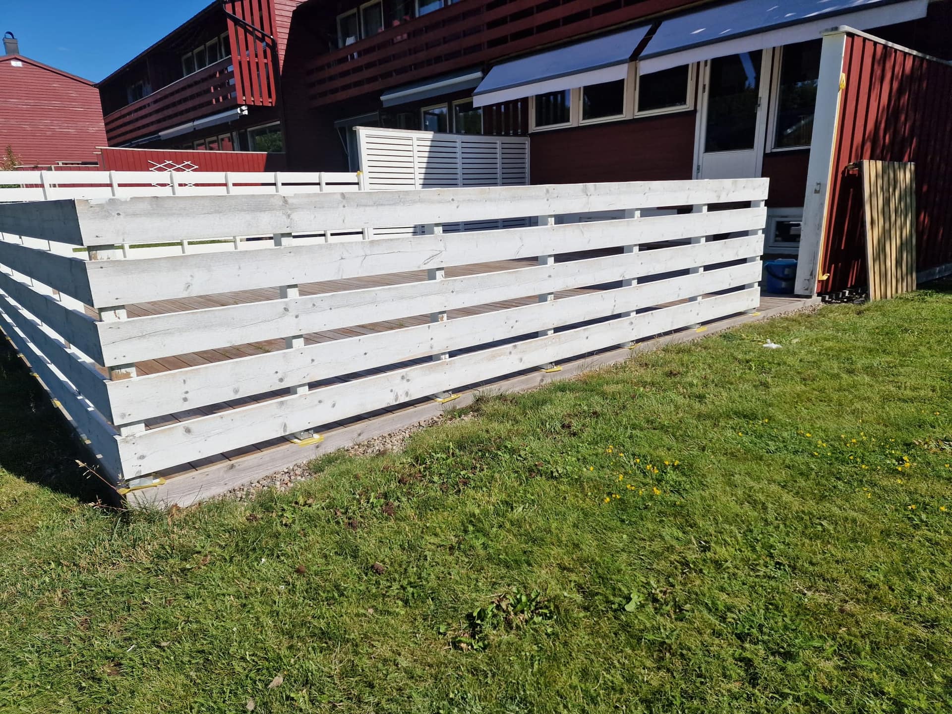 Hvitt terrassegjerde foran rødt rekkehus