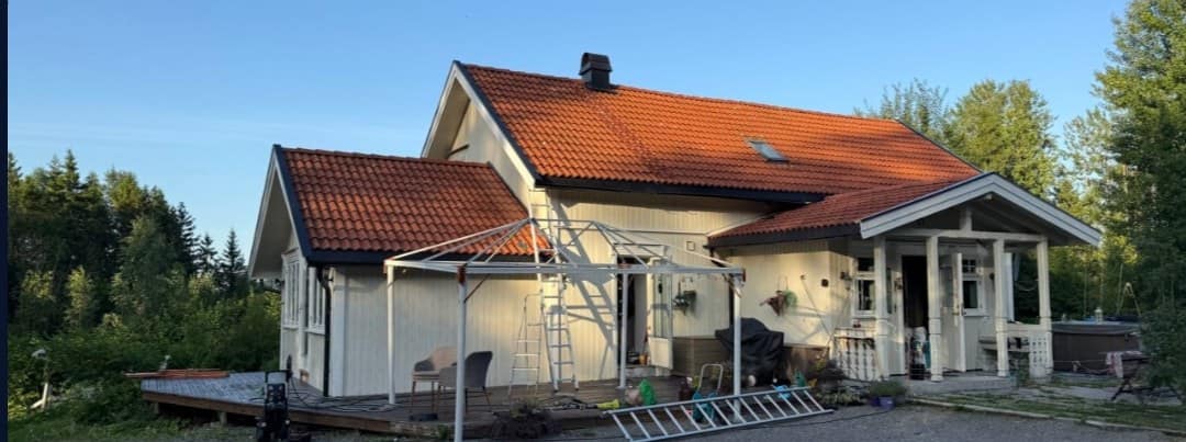 Hvit enebolig med rødt tak i kveldslys under maling